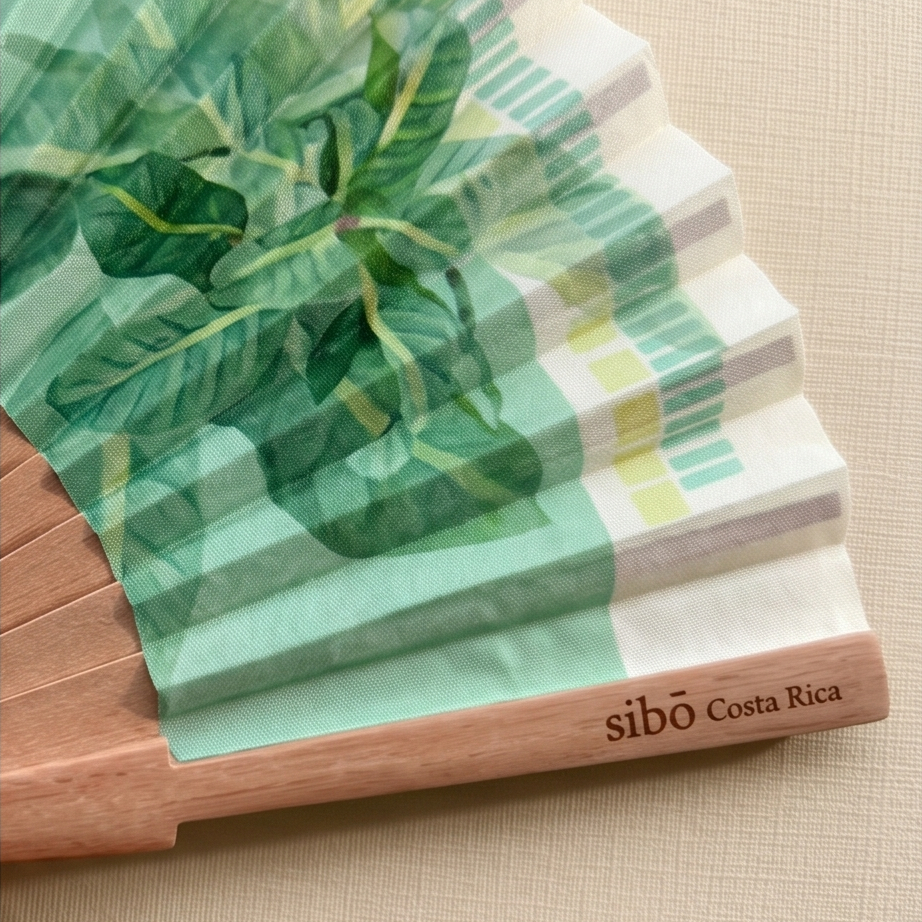 close up view of a sloth inspired hand wooden fan, featuring 'sibo Costa Rica' branding.